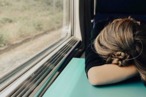 A woman sitting on a train, looking down, symbolising self-sabotage and the negative effects it can have on one's mental health.