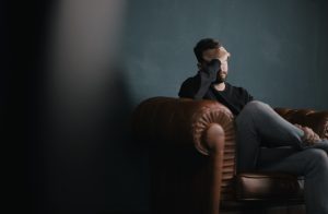 A man with his head in his hands, looking stressed and anxious, as a result of his inner critic